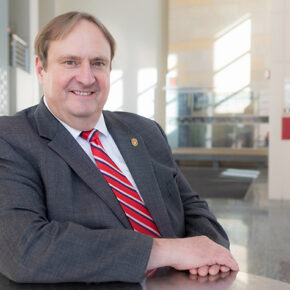 An environmental portrait of Steve Swanson in the sun-brightened atrium of the School of Pharmacy.