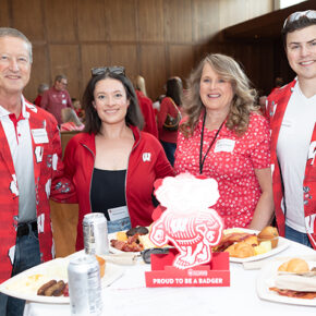 Denise Kachel with her husband, son, and daughter, all dressed in Badger red. The two men wear sport coats with Bucky badger and Ws on them.