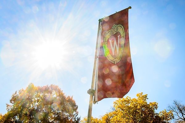 Sunlight shines through an iconic W crest banner on Bascom Hill at UW-Madison.