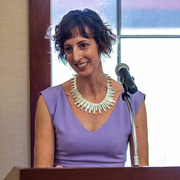 Allison Gardener stands at a podium to receive her PharmTox Alum of the Year award