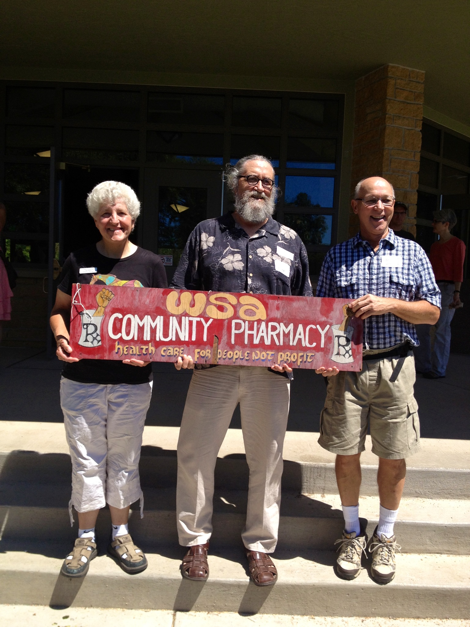 Jane Greischar, David LaLuzerne, and Peter Kiesch holding a Community Pharmacy Sign