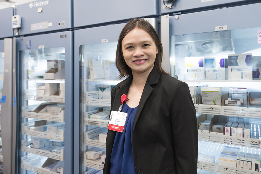 Connie Vo in front of refrigerated storage in a pharmacy