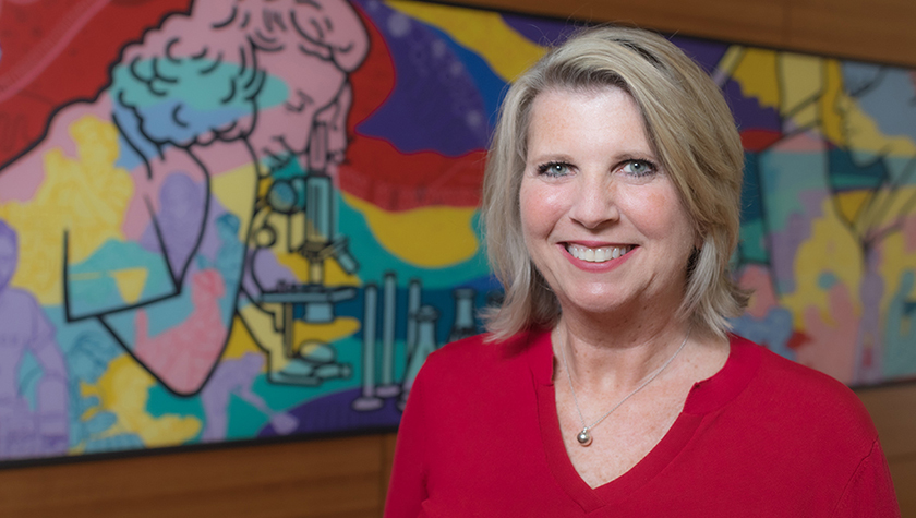 A portrait of Debra Fluno in front of a colorful mural
