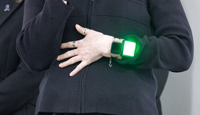 A close-up image of a woman's wrist wearing a watch with a glowing green screen