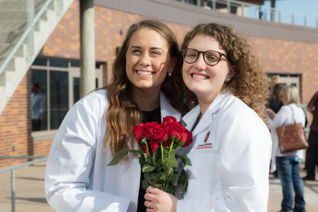 Students together holding roses after White Coat Ceremony