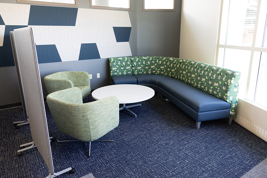 A colorful L-shaped couch and green lounge chairs in the Commons