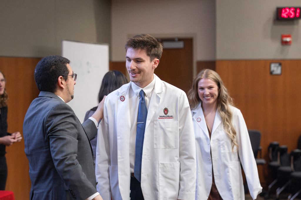 Ed Portillo pats the arm of a student in a white coat