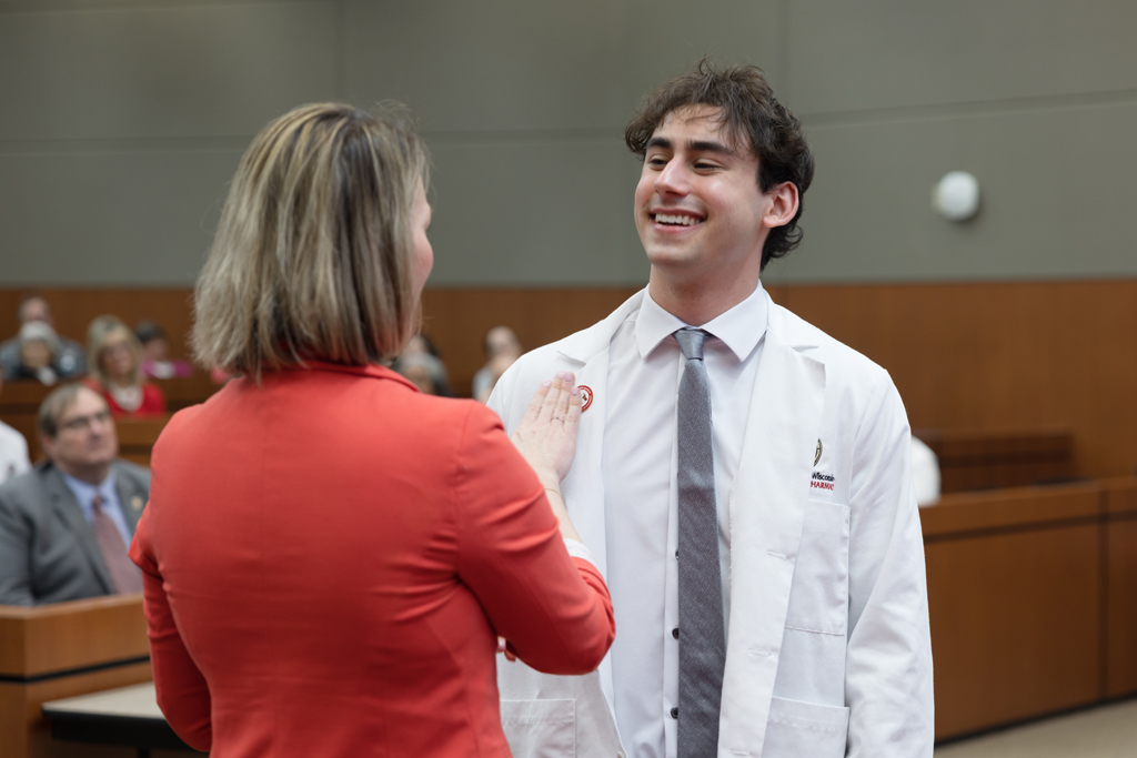A PharmD student receives a pin on the lapel of their white coat