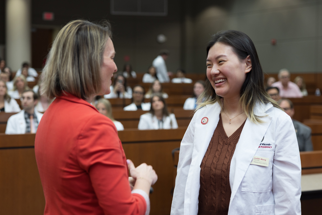 A PharmD student receives a pin on the lapel of their white coat