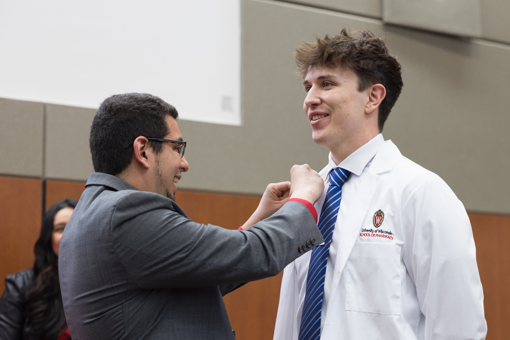 A PharmD student receives a pin on the lapel of their white coat