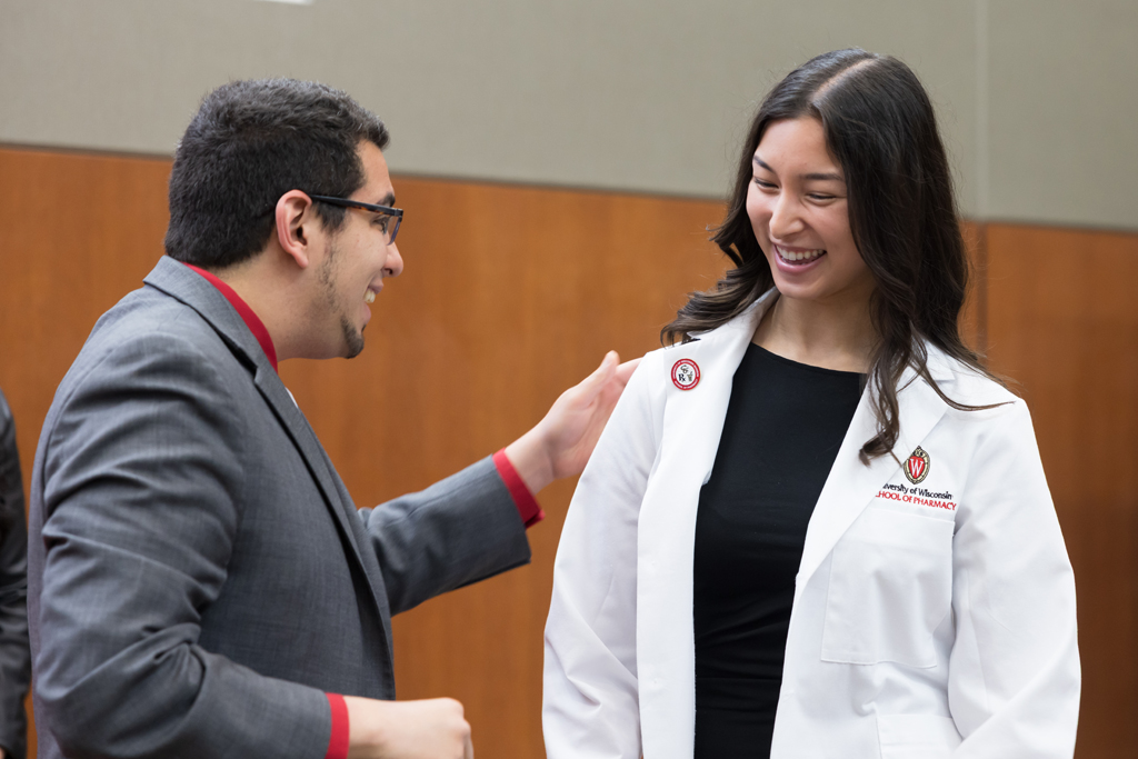 A PharmD student receives a pin on the lapel of their white coat
