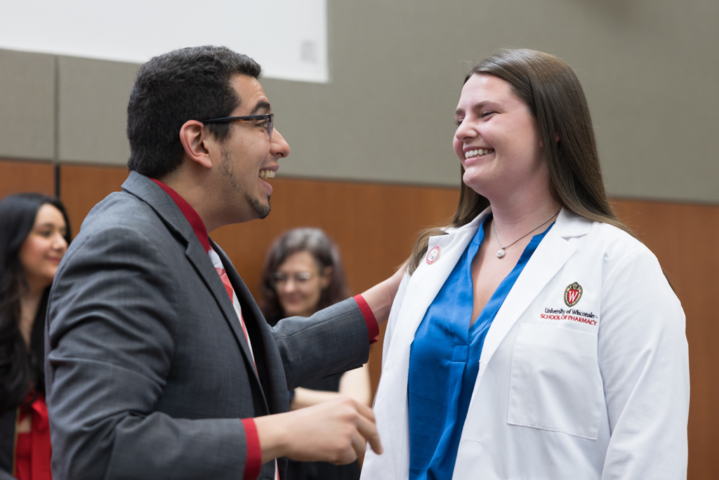A PharmD student receives a pin on the lapel of their white coat