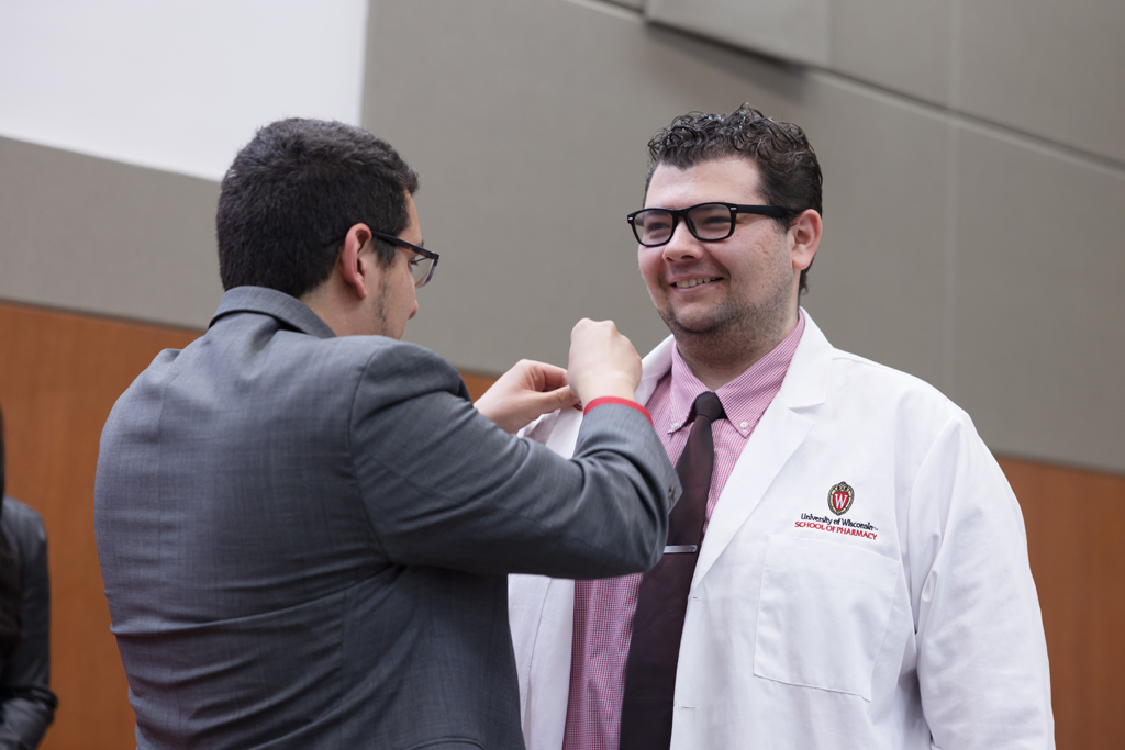 A PharmD student receives a pin on the lapel of their white coat