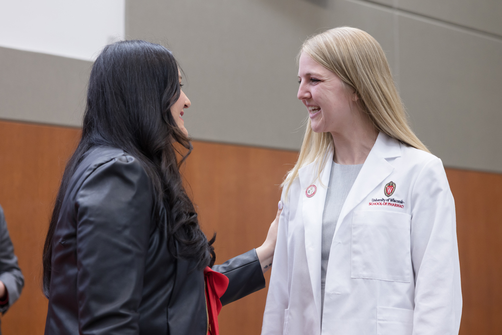 A PharmD student receives a pin on the lapel of their white coat