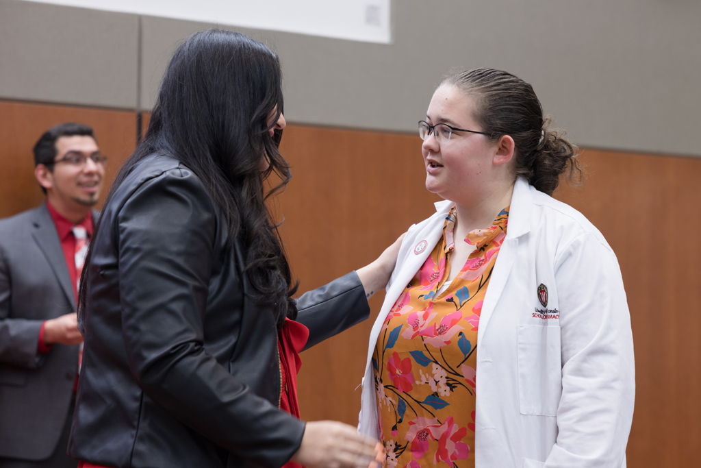 A PharmD student receives a pin on the lapel of their white coat