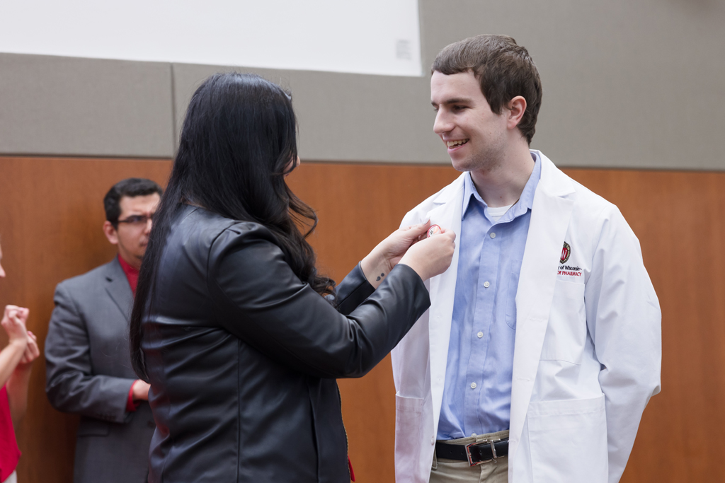 A PharmD student receives a pin on the lapel of their white coat