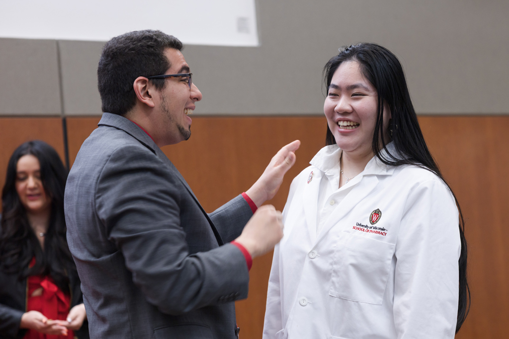 A PharmD student receives a pin on the lapel of their white coat
