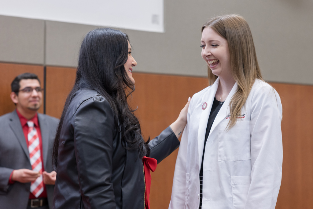 A PharmD student receives a pin on the lapel of their white coat