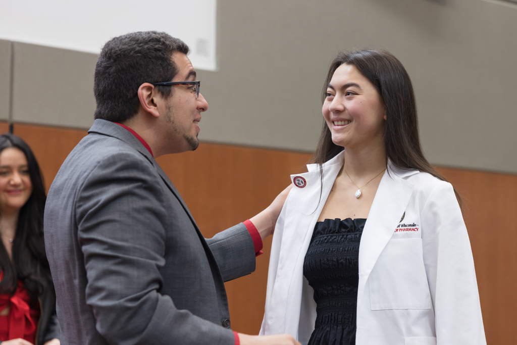A PharmD student receives a pin on the lapel of their white coat