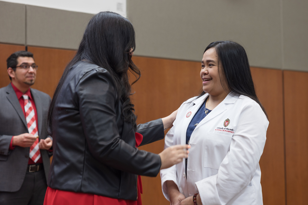 A PharmD student receives a pin on the lapel of their white coat