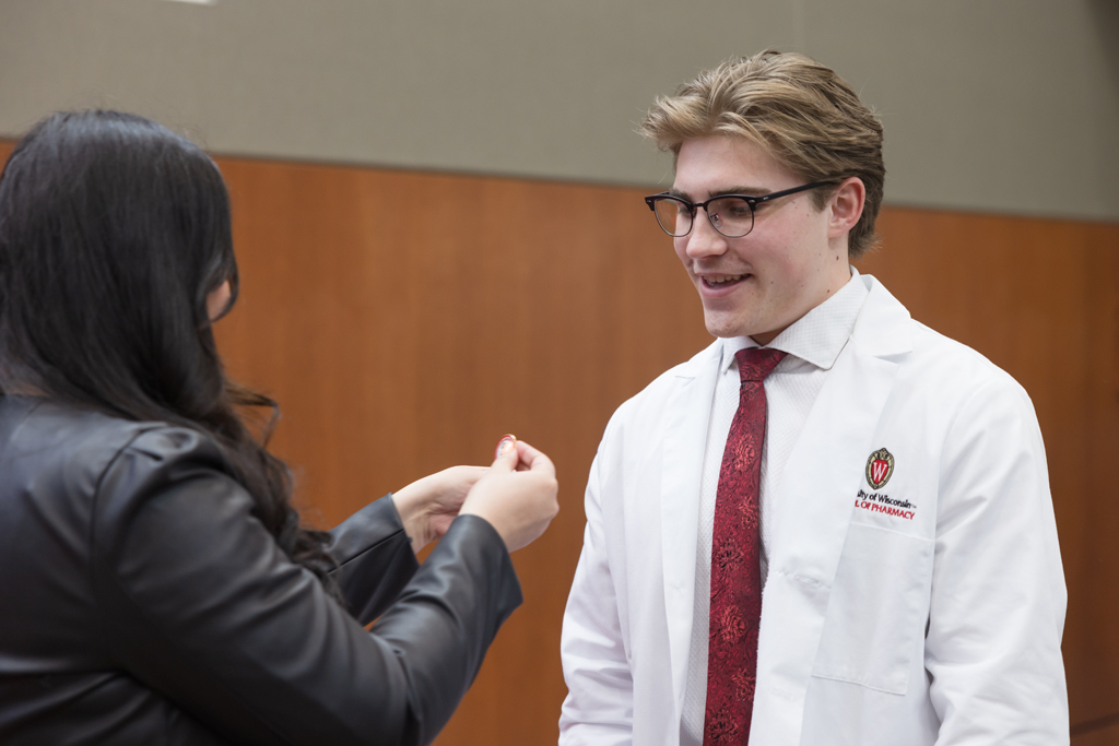 A PharmD student receives a pin on the lapel of their white coat