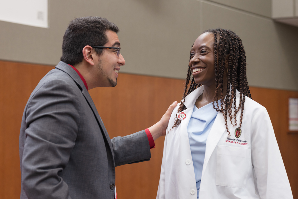 A PharmD student receives a pin on the lapel of their white coat