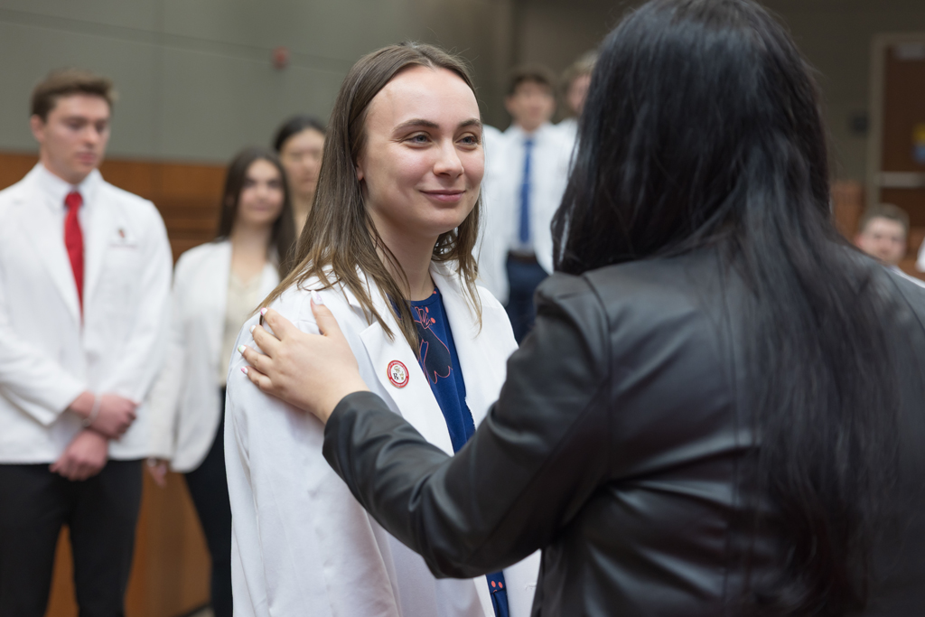 A PharmD student receives a pin on the lapel of their white coat