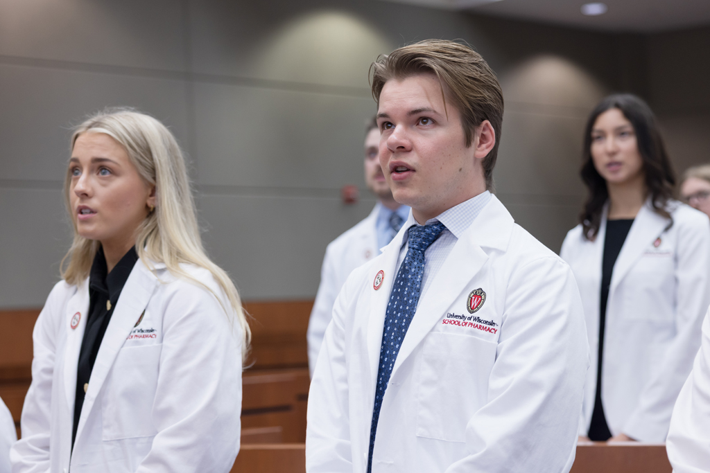 PharmD students stand in their white coats and recite the Oath of the Pharmacist