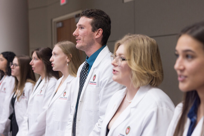 PharmD students stand in their white coats and recite the Oath of the Pharmacist