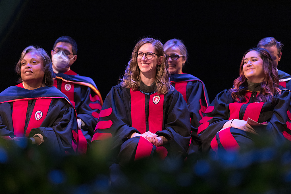 A group of faculty applaud onstage.
