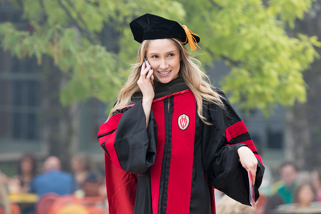 A School of Pharmacy graduate walks outside and speaks on the phone.