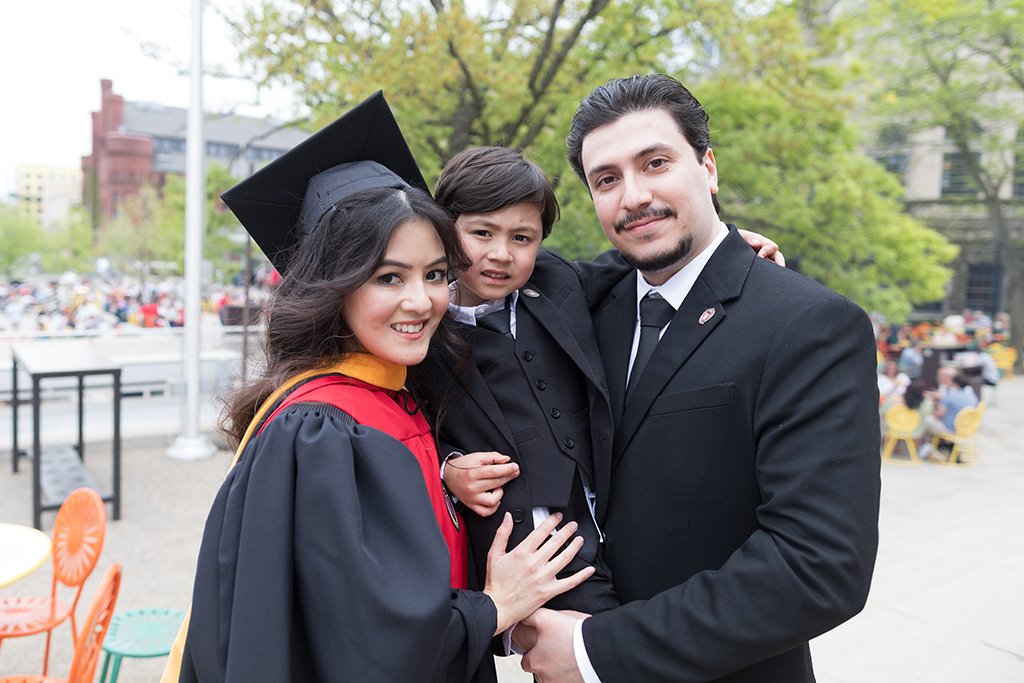 A School of Pharmacy graduate celebrates outside with her family.