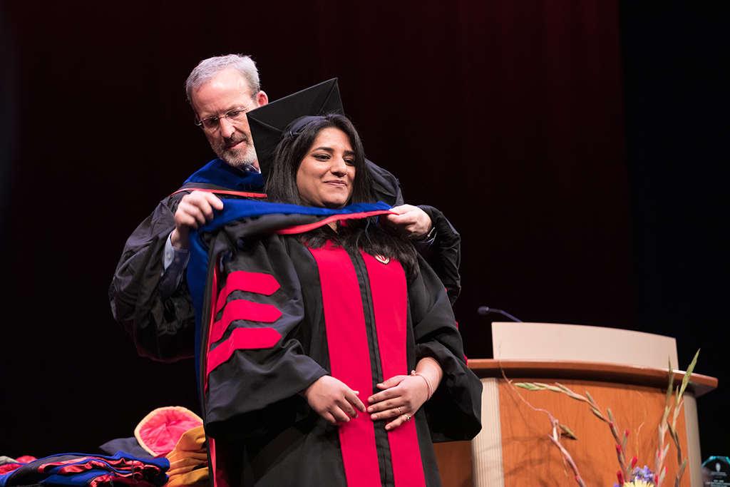 Dave Mott bestowing a hood upon a graduate student at the hooding ceremony