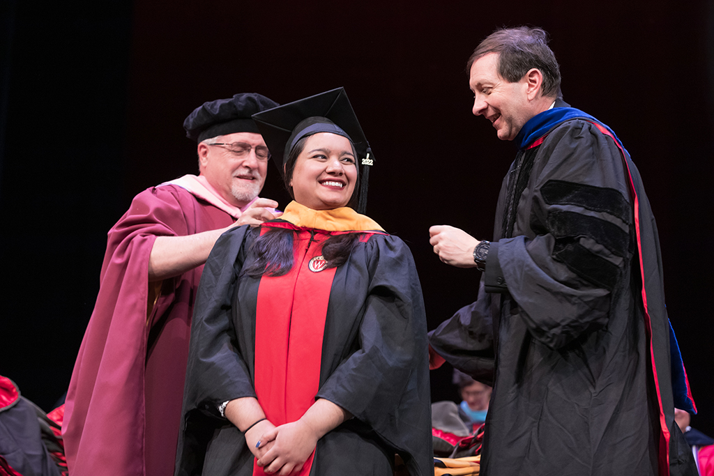 Assistant Dean Melgardt deVilliers and another professor putting the hood on a graduate student