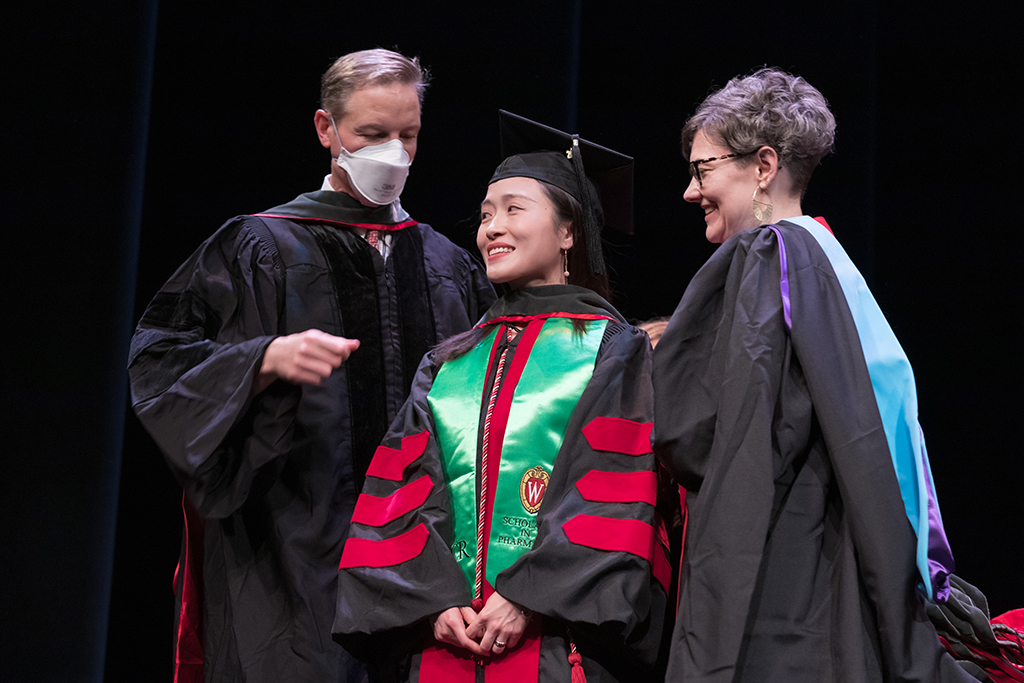 Class of 2022 PharmD graduate Wenxuan Cai receives her hood from Professor John Dopp and Advisor Rebecca Beebe