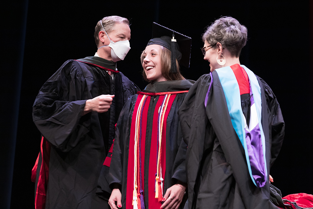 Class of 2022 PharmD graduate Jordyn Kettner receives her hood from Professor John Dopp and Advisor Rebecca Beebe