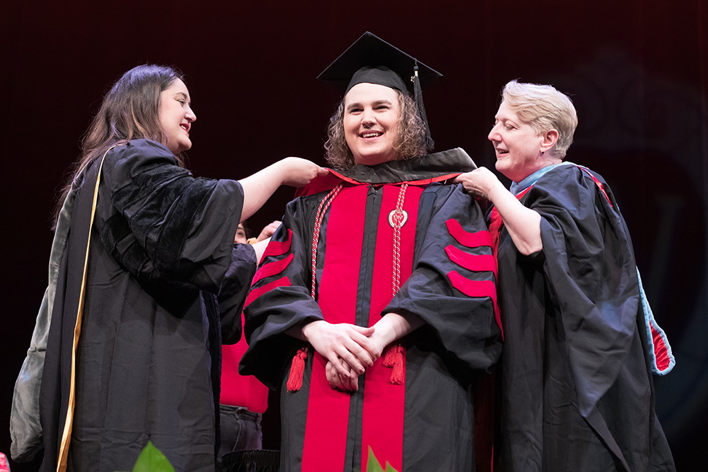 Class of 2022 PharmD graduate Katelyn Johnson receives her hood from professors Marina Maes and Karen Kopacek