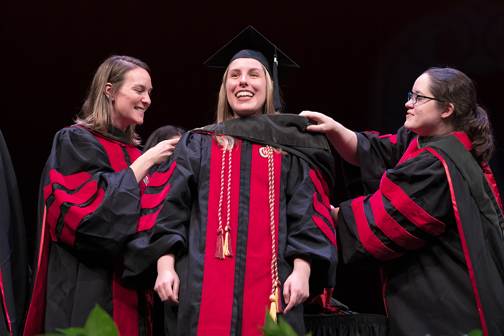 Class of 2022 PharmD graduate Cynthia May receives her hood from professors Kate Rotzenburg and Amanda Margolis