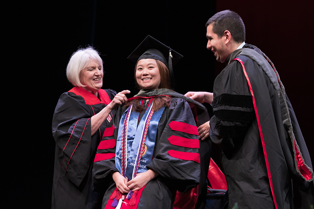 Class of 2022 PharmD graduate Linda Zheng receives her hood from Professors Ed Portillo and Bonnie Fingerhut