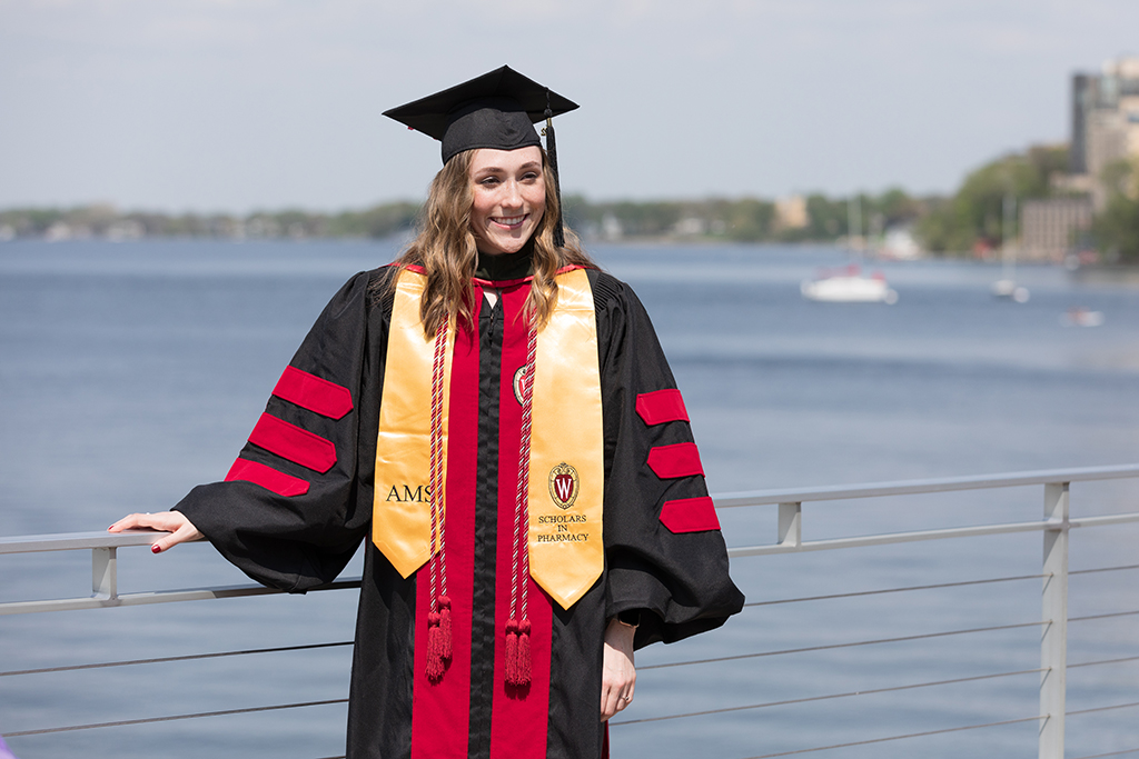 Class of 2022 PharmD graduate Emily Willey poses in her cap and gown at Memorial Union Terrace after the Hooding Ceremony