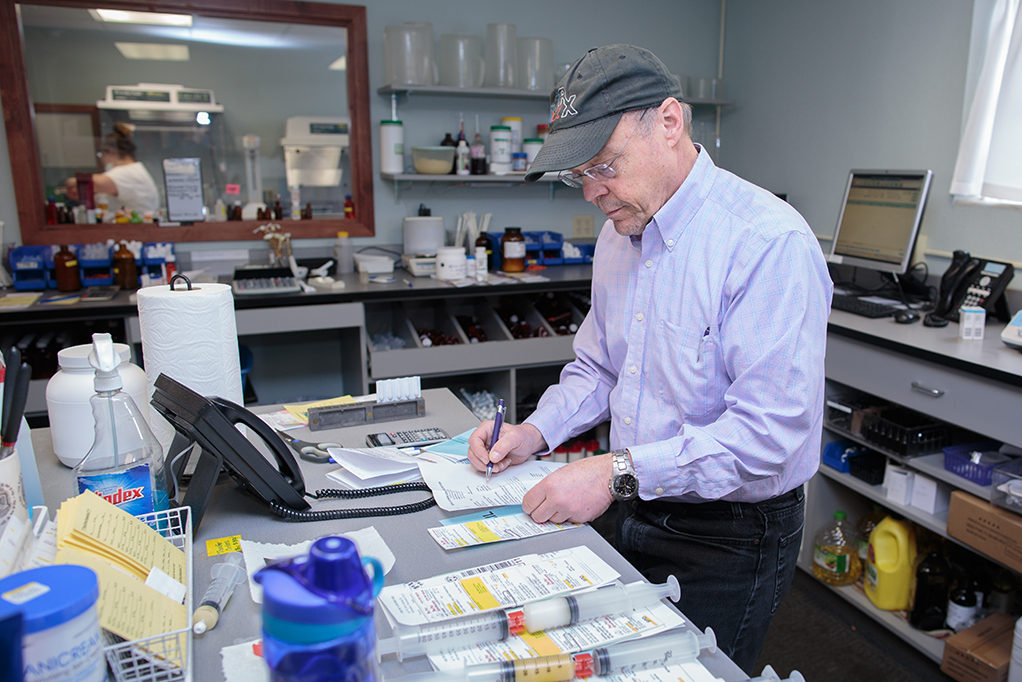 Jeff Langer working with counter full of prescriptions and syringes