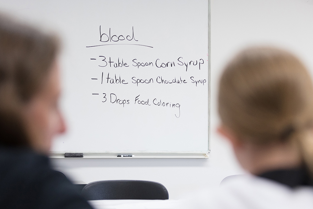 The recipe for blood written on a whiteboard: 3 tablespoons corn syrup, 1 tablespoon chocolate syrup, 3 drops food coloring