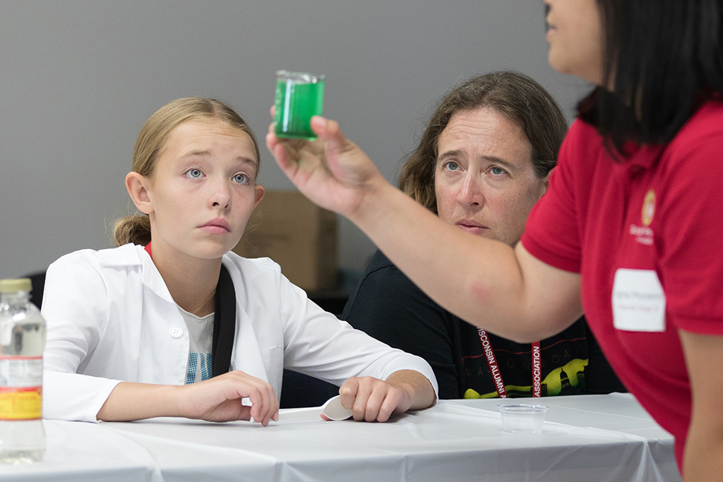 Attendees look at a cup of green liquid held up by a facilitator