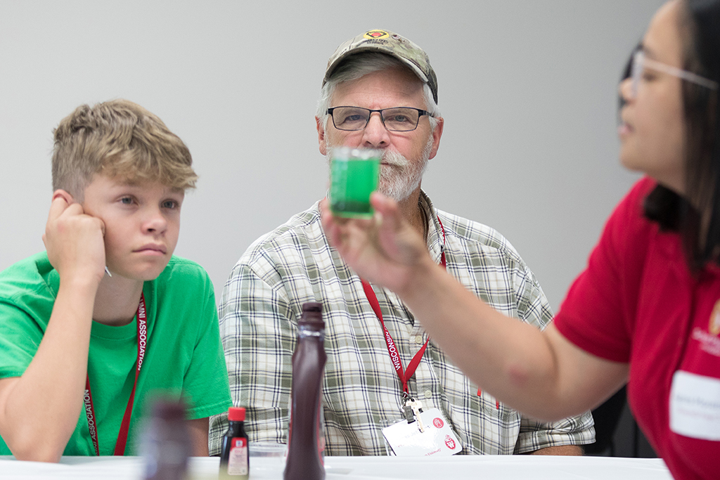 Attendees look at a cup of green liquid held up by a facilitator