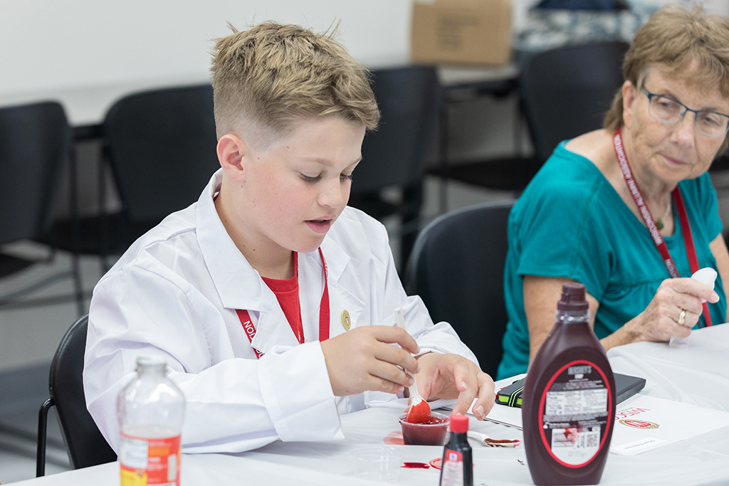 A young attendee mixes a red liquid in a small cup