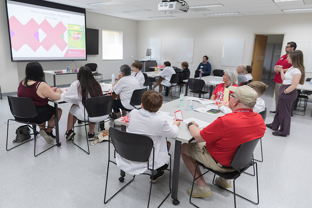 Tables of attendees look at a projection screen that displays a box of Zyrtec