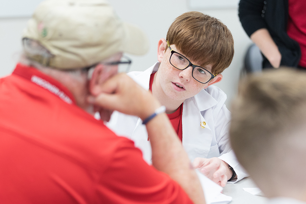 A young attendee in a white coat looks at an older adult man