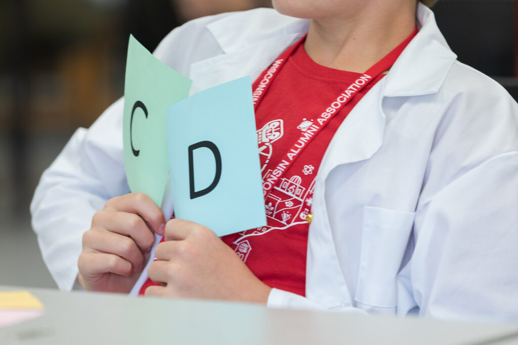 A young attendee holds up papers, one with a letter C and one with a letter D