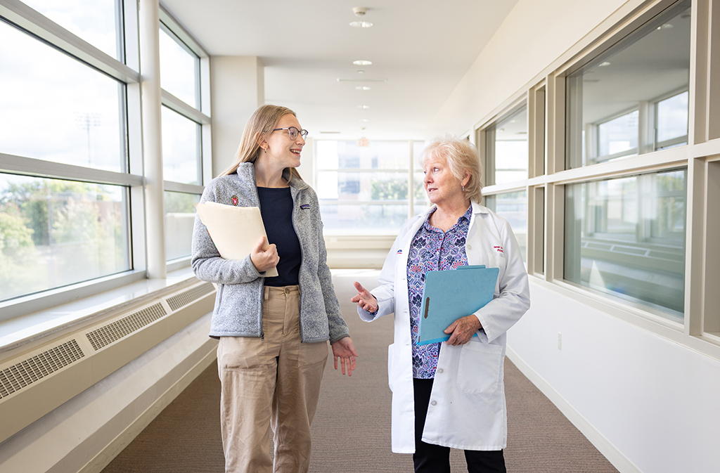 A pharmacy resident and Sarah Lentz walk down a hallway