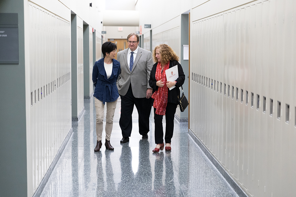 Chancellor Mnookin walking and talking with Steve Swanson and Michelle Chui down a hallway